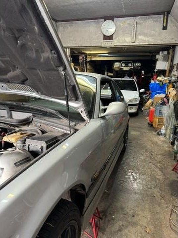 ボンネットを開けて整備中の車